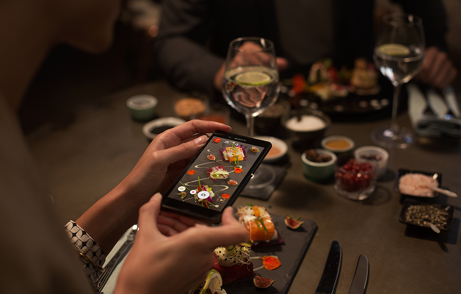 Пользователь снимает на Xperia Z3+ блюда в слабо освещенном ресторане
